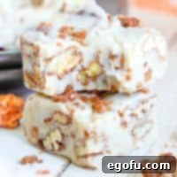 A bite taken out of one piece of Candied Pecan Fudge sitting on top of another piece of fudge.