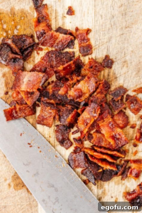 Crispy Holiday Brussels Sprouts 16 Chopped, cooked bacon on a cutting board, ready to be added to the dish.