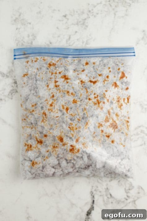 Harvest Puppy Chow Delight 11 A sealed Ziploc bag containing powdered sugar and chocolate-coated cereal, mid-shake.