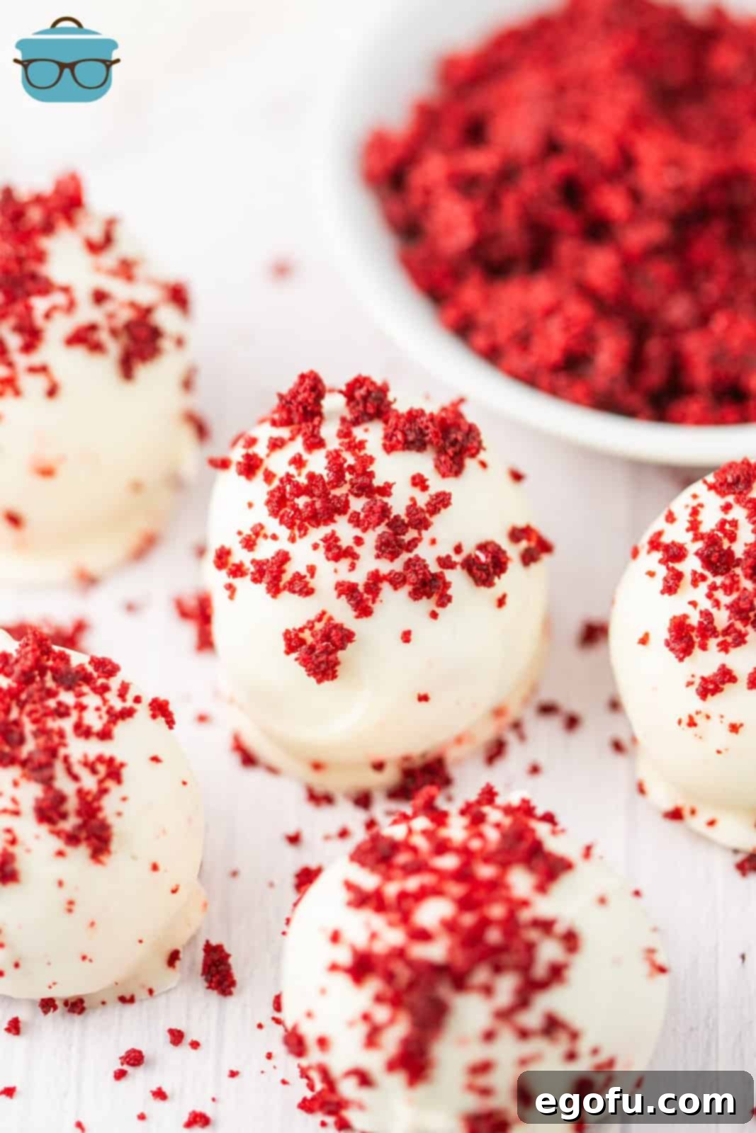 A few Red Velvet Cake Balls with some red velvet cake pieces sprinkled on top.