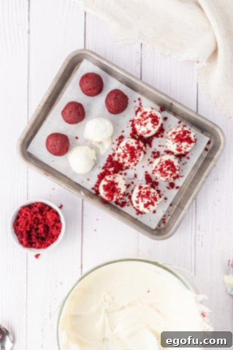 A baking sheet with some red velvet cake balls in a cream cheese frosting.