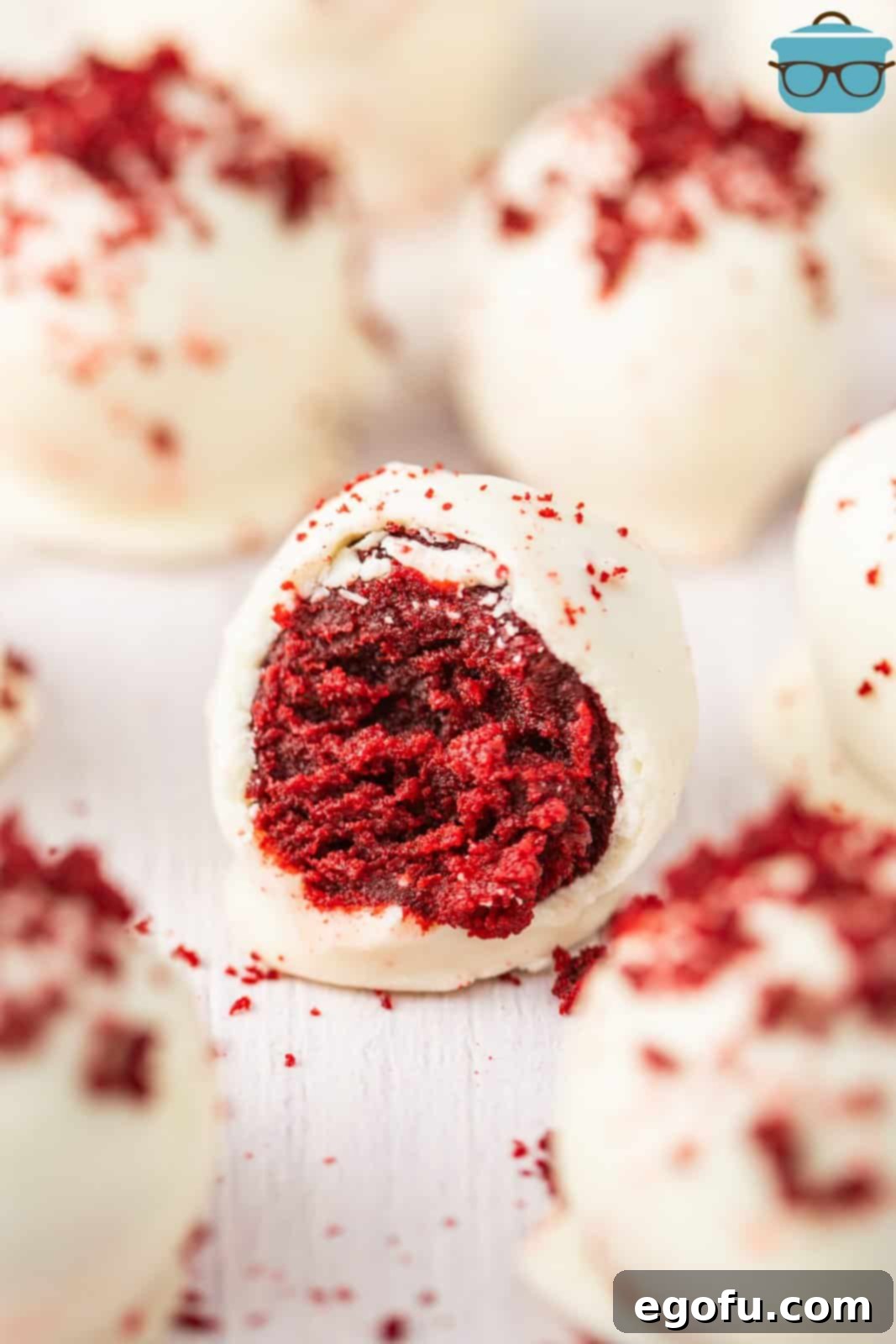 A few Red Velvet Cake Balls with some sprinkles on top with one missing a bite.