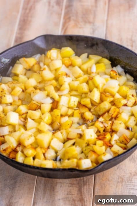 Crispy potatoes cooking in a skillet.