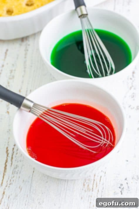 Two bowls containing vividly colored red and green Jell-O mixtures, each with a whisk, showing the results of adding food coloring.