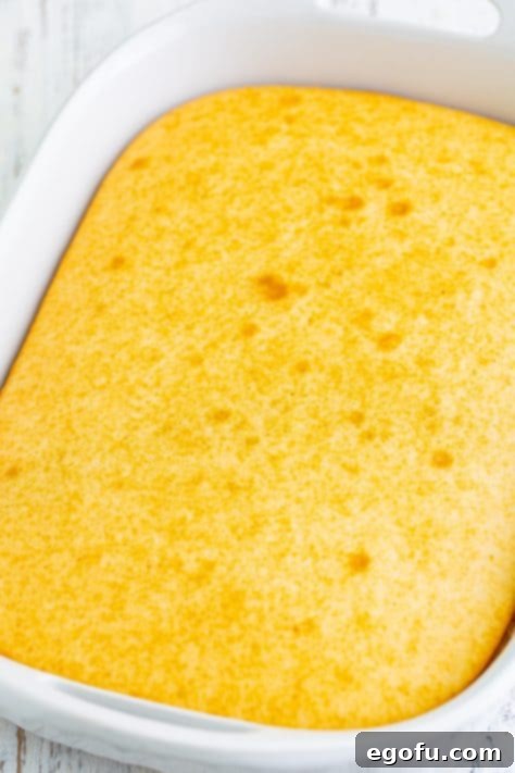 A perfectly baked white cake in a baking dish, freshly removed from the oven and cooling.