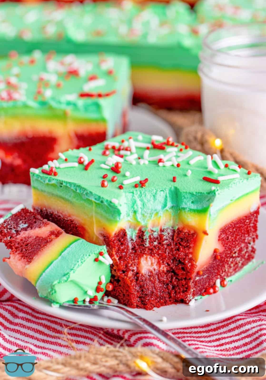 A slice of Christmas Jello Poke Cake with a fork holding a bite on a plate.
