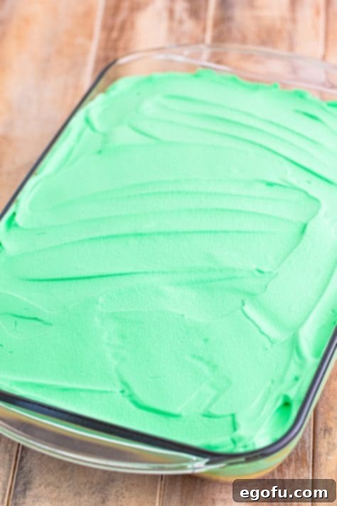 Green whipped topping spread on a cake.