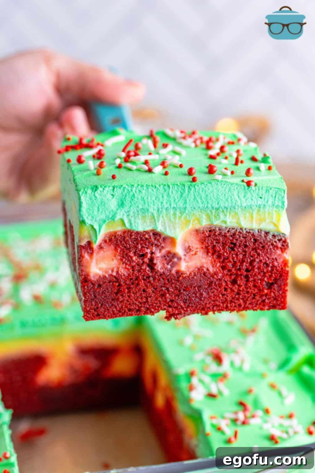 A slice of Christmas Jell-o Poke Cake being lifted above the rest of the cake.