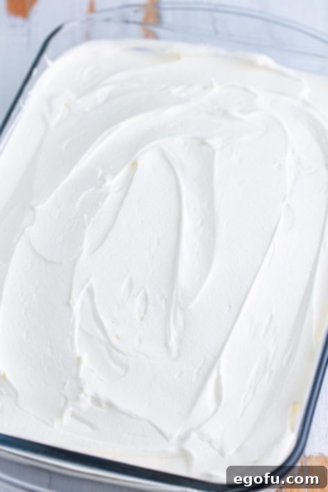 Whipped topping spread over a chocolate poke cake.