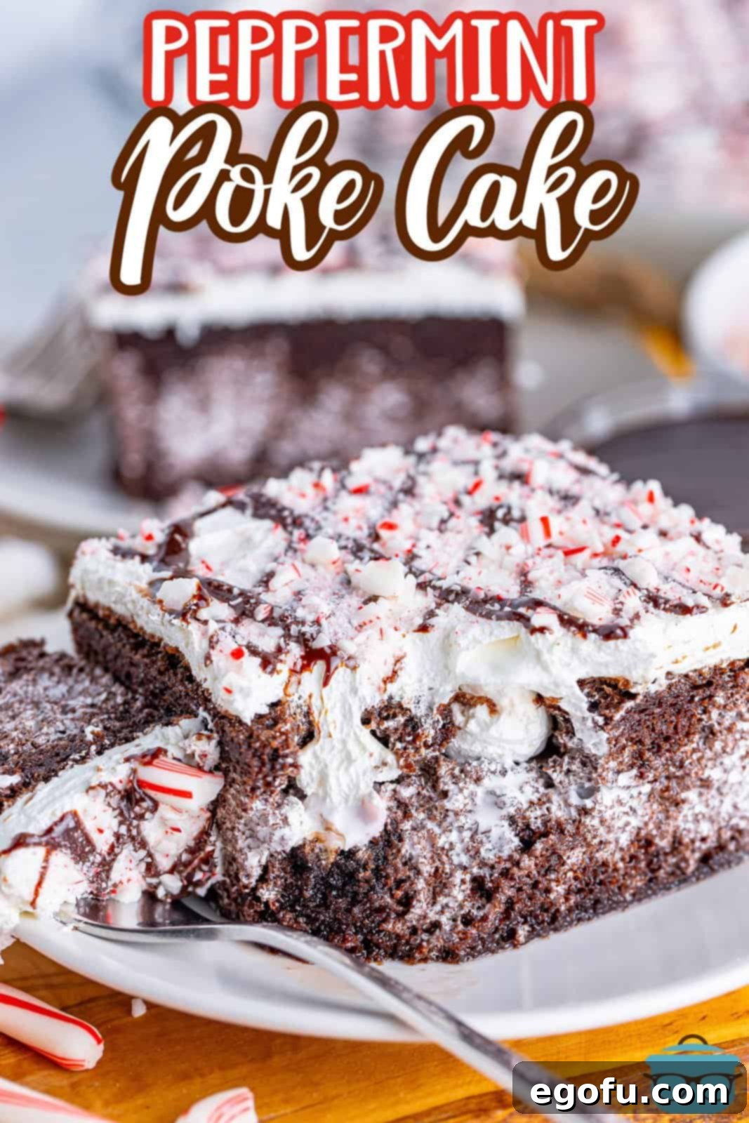 Close up looking at a piece of Peppermint Poke Cake with a fork taking a bite, showing the layers of cake, filling, and topping.