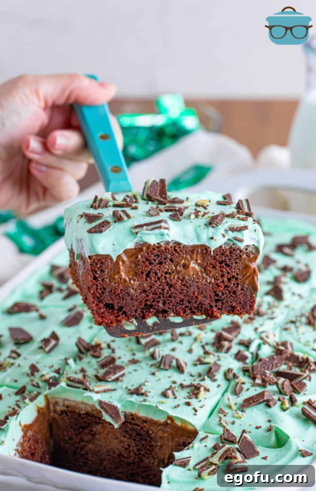 Peppermint Patty Poke Cake 7 A delicious slice of Mint Chocolate Poke Cake being carefully lifted from the baking pan, showcasing its distinct layers.