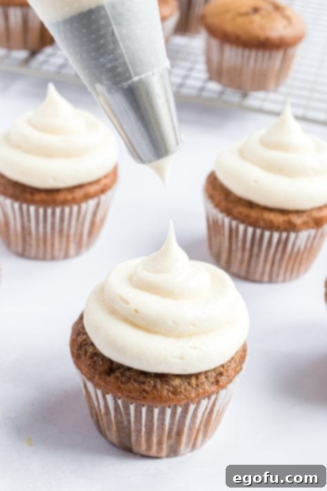 Cozy Gingerbread Cupcakes 14 piping frosting onto gingerbread cupcakes.