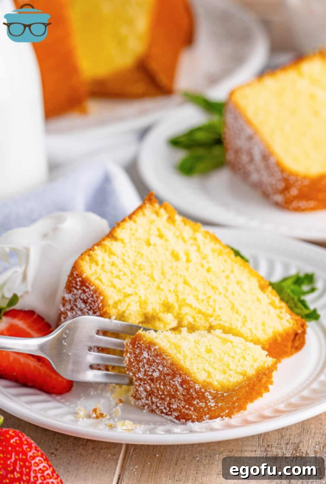 A perfectly golden slice of Southern Pound Cake on a white plate, with a fork poised to take a bite.