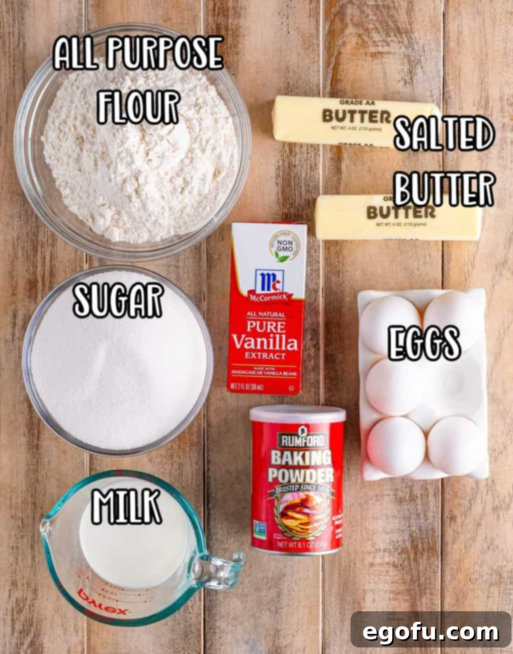 A flat lay photograph showcasing all the primary ingredients for Southern Pound Cake: flour, butter, eggs, vanilla extract, baking powder, milk, and sugar.