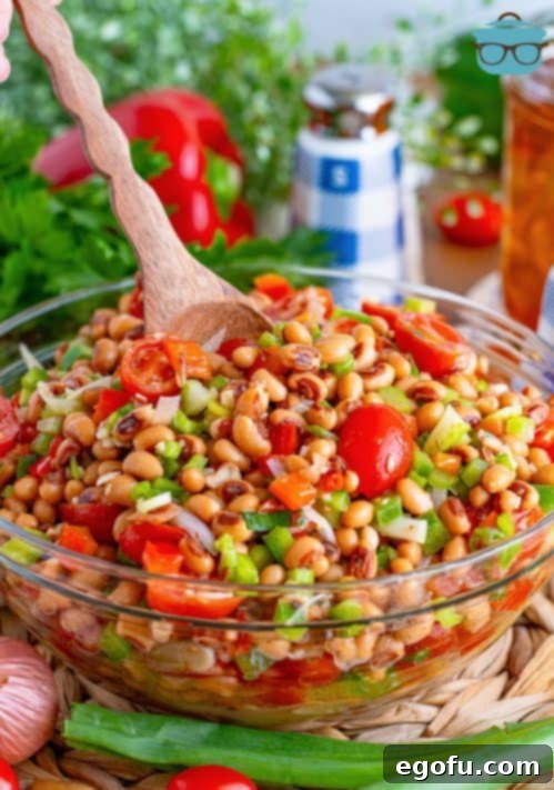 Zesty Black Eyed Pea Salad 8 A wooden spoon in a bowl of Black Eyed Pea Salad, highlighting its fresh ingredients and creamy texture.