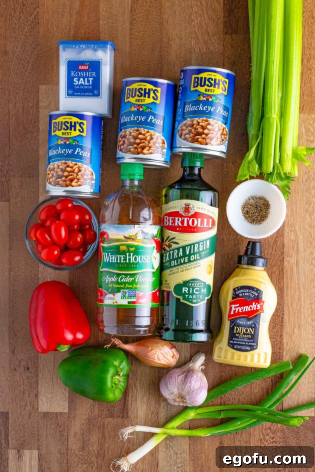 Zesty Black Eyed Pea Salad 4 A vibrant flat lay of all ingredients for Black Eyed Pea Salad: black eyed peas, shallots, celery, cherry tomatoes, red bell pepper, green bell pepper, green onion, olive oil, apple cider vinegar, garlic cloves, Dijon mustard, kosher salt, and black pepper.