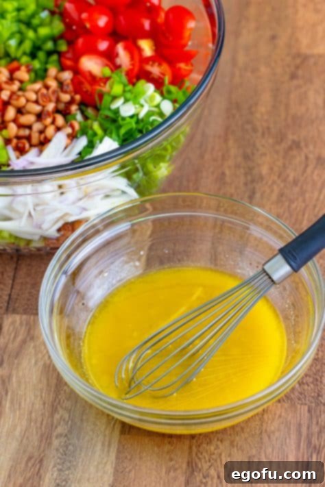 Zesty Black Eyed Pea Salad 6 A glass bowl with olive oil, apple cider vinegar, garlic, dijon mustard, salt, and pepper, ready to be whisked for the dressing.