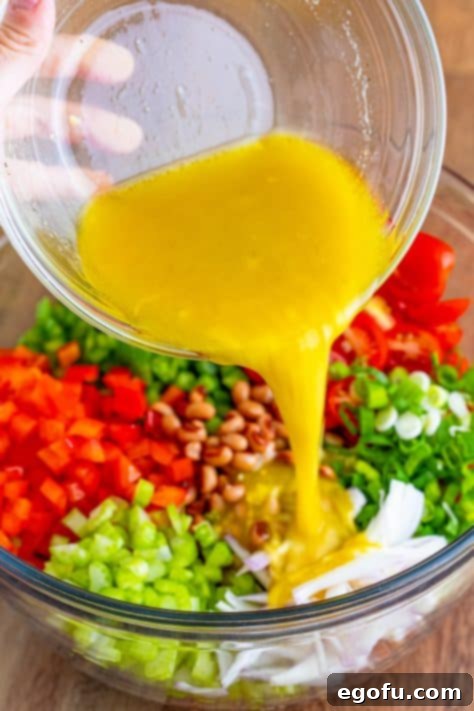 Zesty Black Eyed Pea Salad 7 Homemade vinaigrette being poured over the colorful black-eyed pea salad ingredients.