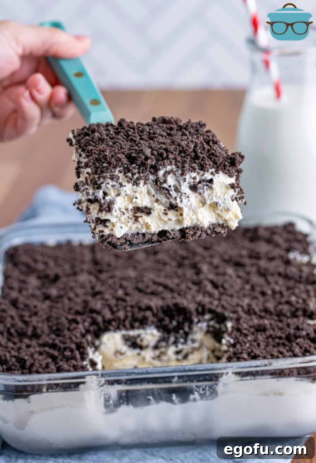 A serving utensil holding a slice of No Bake Oreo Dessert above the rest of the treat.