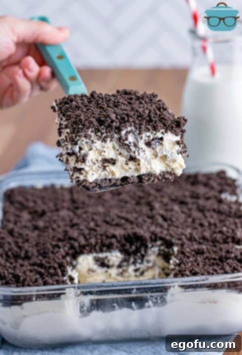 A serving utensil holding a slice of No Bake Oreo Dessert above the rest of the treat.