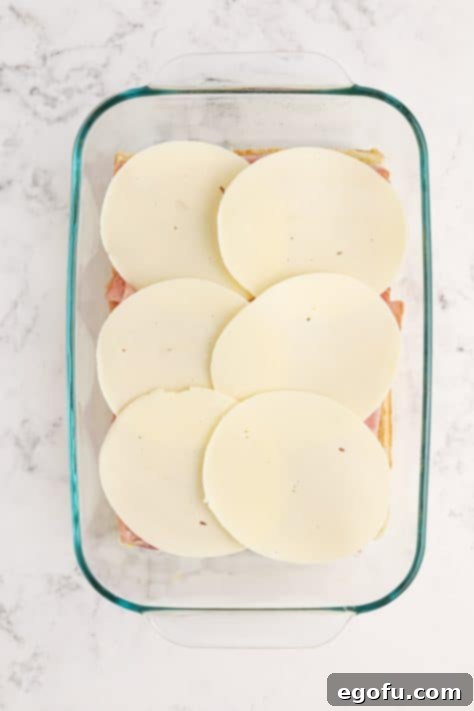 Ham and provolone cheese on top of a mustard mixture on Hawaiian Rolls.