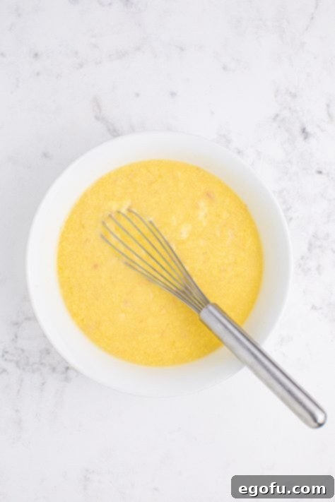 A mixing bowl of cream of chicken soup, chicken broth and minced garlic.
