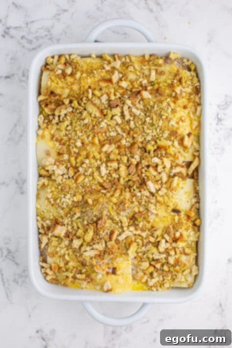 Stuffing mix on top of Swiss cheese covered chicken in a baking dish.