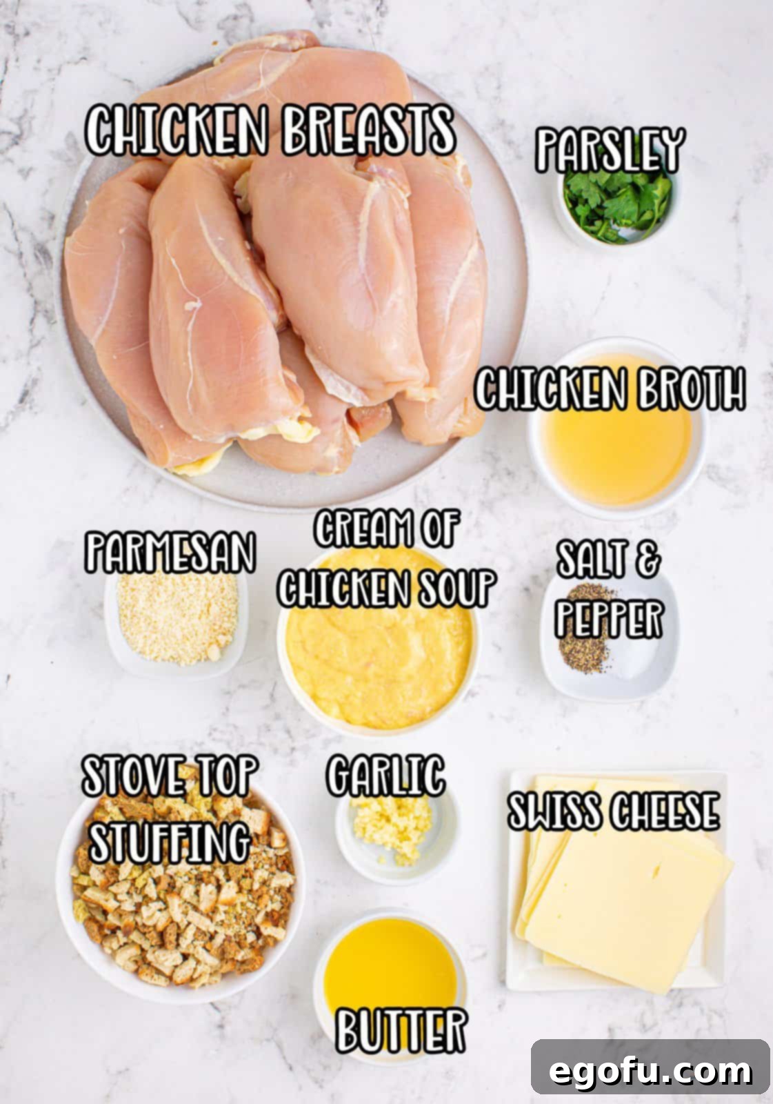 An array of fresh ingredients for Swiss Chicken Casserole: boneless skinless chicken breasts, grated parmesan cheese, salt, pepper, Swiss cheese slices, can of cream of chicken soup, chicken broth, garlic cloves, melted butter, Stovetop stuffing mix, and fresh minced parsley.