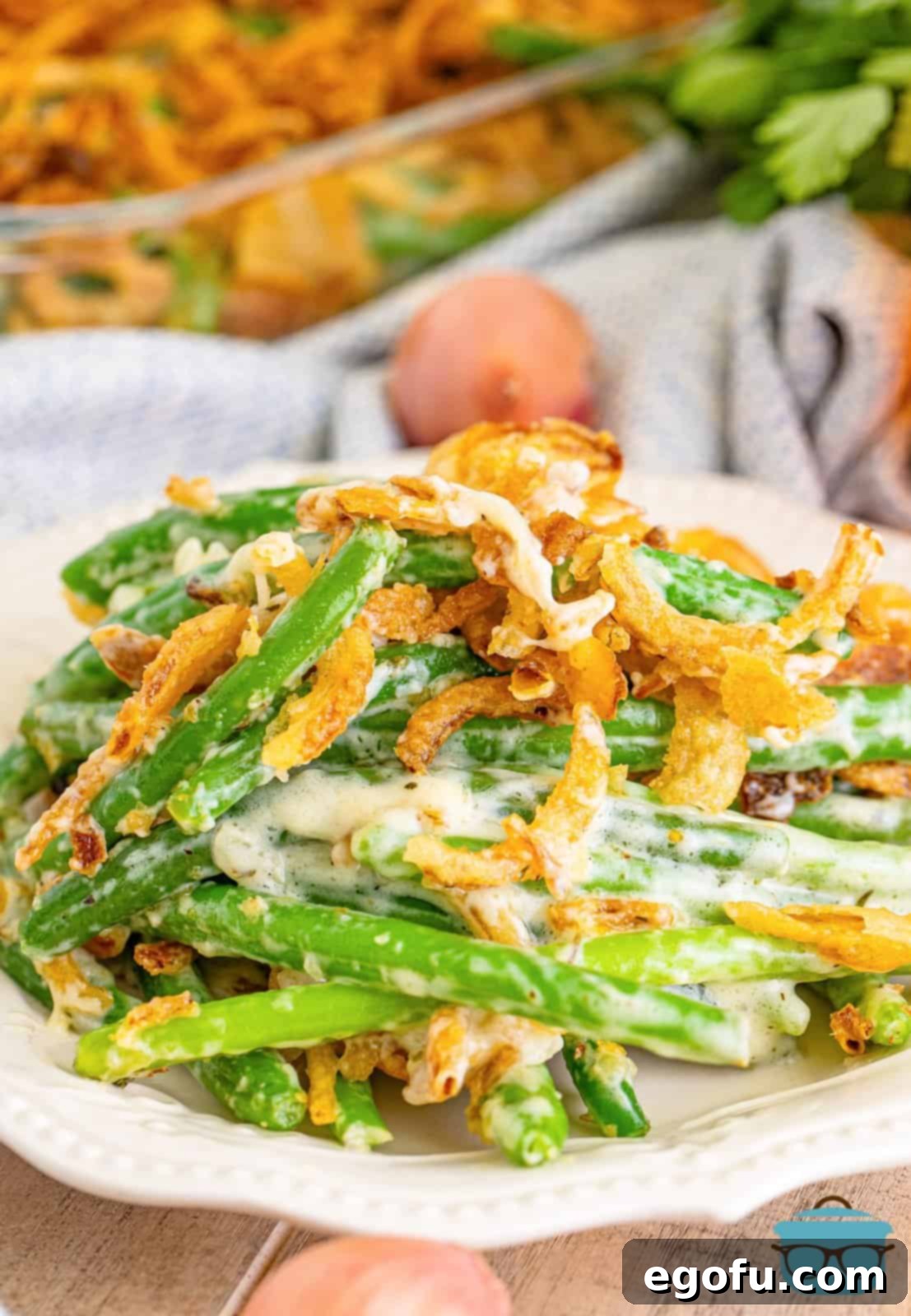 A plate with a heaping pile of Green Bean Casserole with fresh green beans.