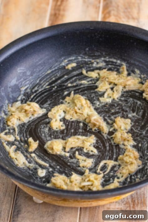 Flour whisked in shallots and spices in a pan.