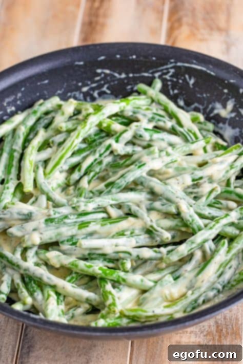 Green beans coated in sauce in a pan.