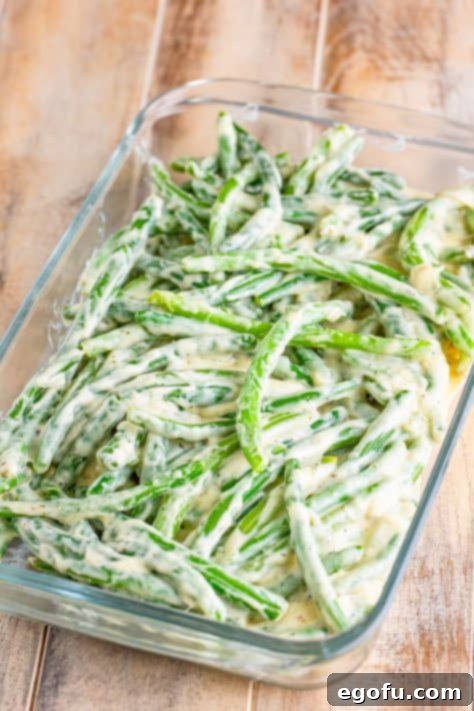Green beans coated in sauce in a baking dish.