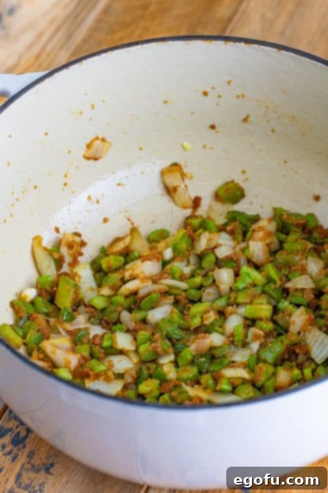 Diced celery, bell pepper, and onion, known as the 'Holy Trinity,' softened and sautéing in a Dutch oven with the roux.