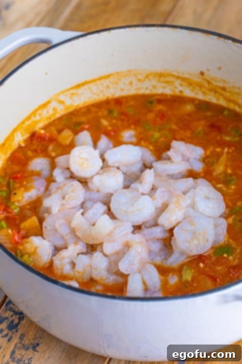 Raw, peeled shrimp added to the rich, simmering étouffée sauce with vegetables and spices, ready to cook to perfection.