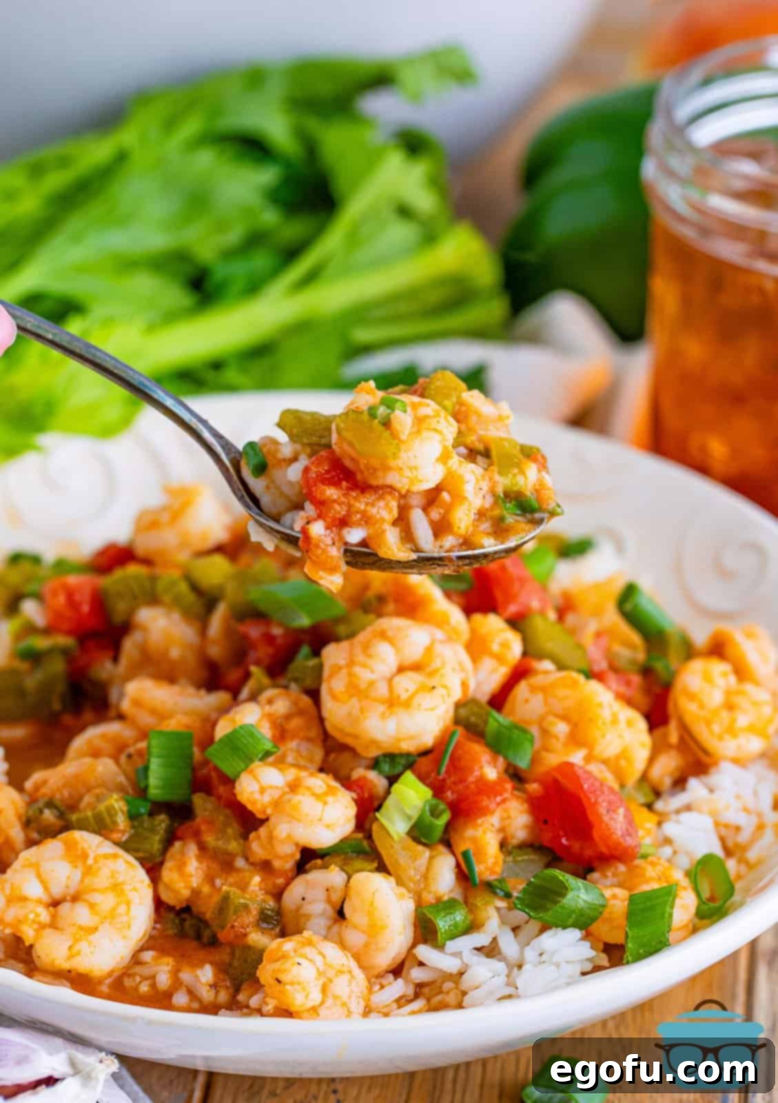 A spoon lifting a perfect bite of Shrimp Étouffée, showing the succulent shrimp and rich, golden sauce, poised above a full plate, inviting diners to enjoy this delicious Southern classic.