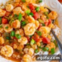 Close up looking at a pile of Shrimp Étouffée, garnished with green onions.