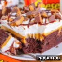 A serving plate with a slice of Reese's Peanut Butter Poke Cake with a fork holding a bite.