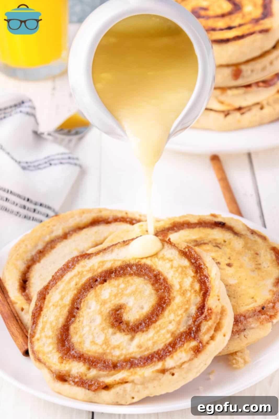 Glaze being poured on a stack of freshly made Cinnamon Roll Pancakes, ready to be served.