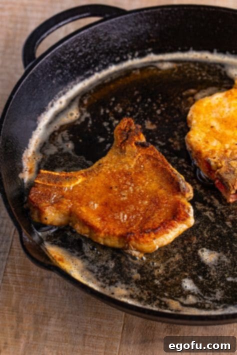 Seasoned and floured cooked pork chops in a pan.
