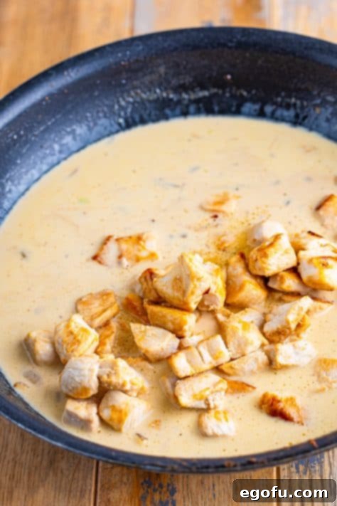 Velvety Chicken and Mushroom Feast 17 Chicken being added to a cream sauce in a skillet.