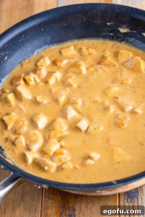 Velvety Chicken and Mushroom Feast 18 Chicken added to a creamy sauce in a skillet.