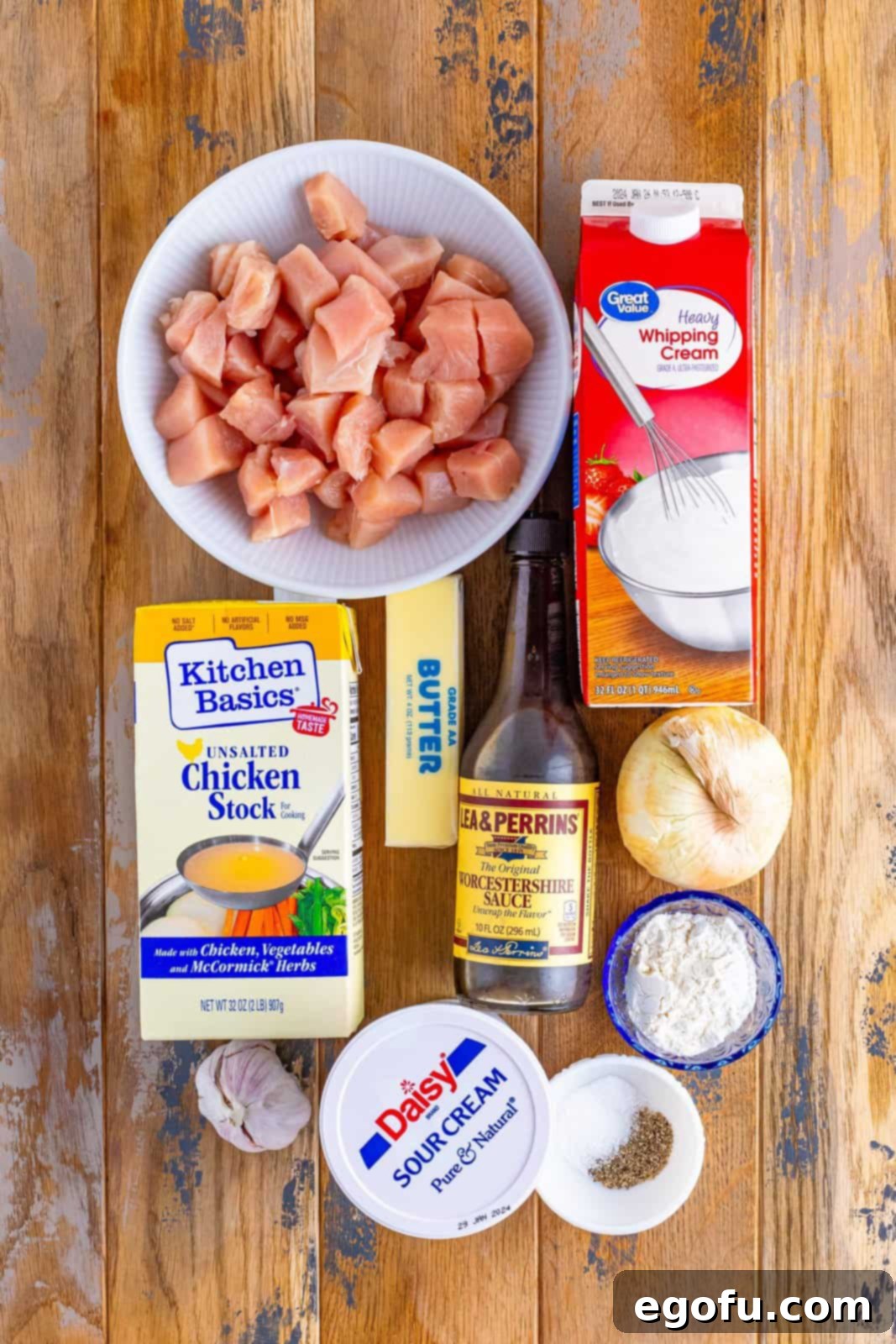 Velvety Chicken and Mushroom Feast 4 A vibrant flat lay showcasing all the fresh ingredients needed for Chicken Stroganoff: diced chicken, heavy cream, butter, chicken broth, Worcestershire sauce, onion, sour cream, flour, garlic, salt, and pepper.