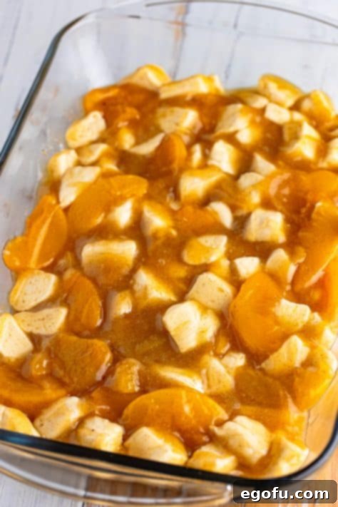 A baking dish with biscuit pieces, peach pie filling, brown sugar, melted butter, vanilla, and cinnamon.