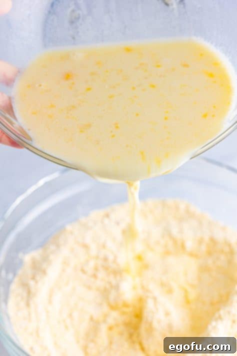 Wet ingredients being poured into the dry ingredients for corn dog batter.