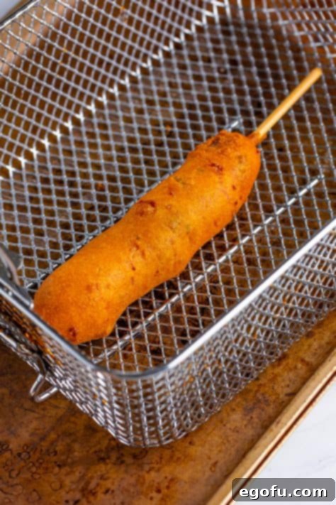 A fried Jalapeno Cheddar Corn Dog in a fryer basket.