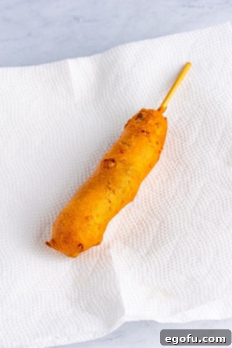 A fried Jalapeno Cheddar Corn Dog on a paper towel.