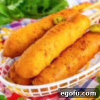 A pile of golden-brown Jalapeno Cheddar Corn Dogs in a basket, ready to be served.