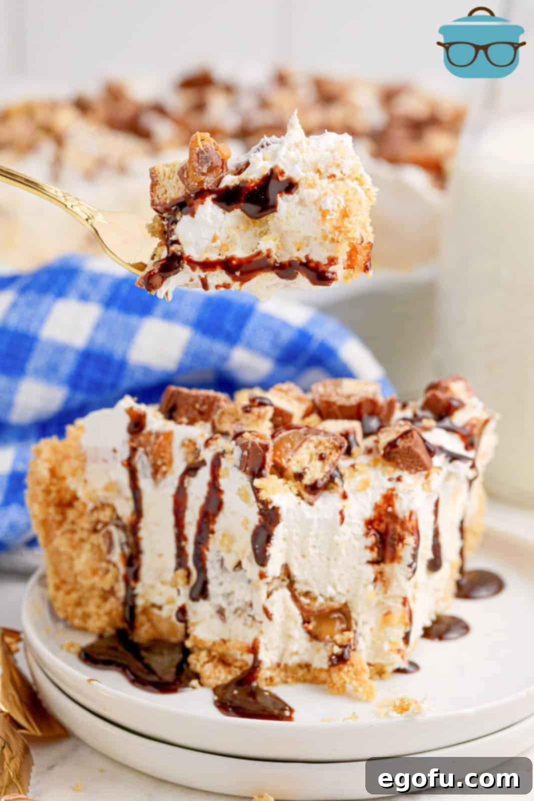 A fork holding a bite of No Bake Twix Pie above a slice of it.