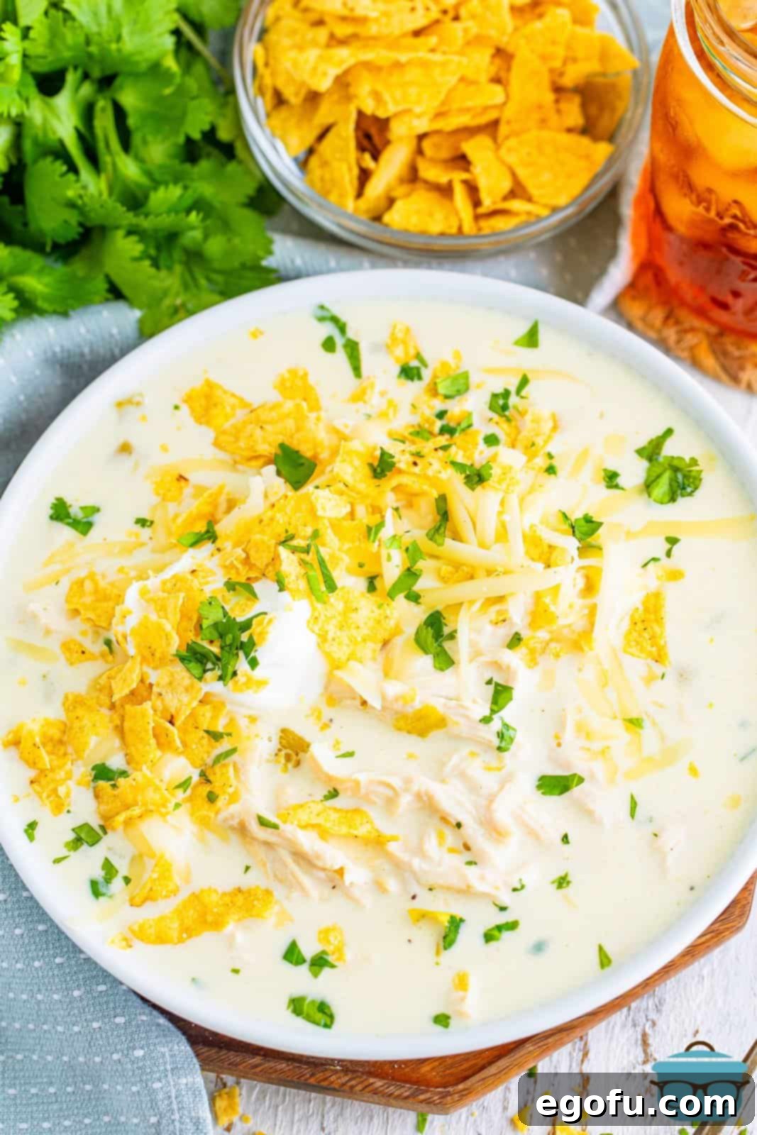 A large pot of homemade White Chicken Enchilada Soup, garnished with fresh cilantro and crushed tortilla chips.