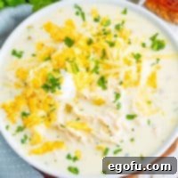 Looking down on a large white bowl of White Chicken Enchilada Soup, garnished with cilantro.